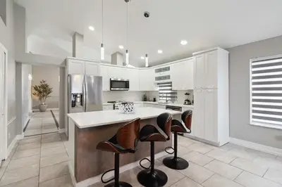 a kitchen with white cabinets and bar stools at Disney Heated Pool & Arcade Home 15 mins to Park in Kissimmee