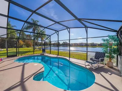 a swimming pool in a glass house with a view of a lake at Holiday Home Moderne Villa mit Seeblick nur wenige Minuten von Disney entfernt by Interhome in Kissimmee