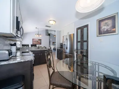 a kitchen with a glass table and a stainless steel refrigerator at Holiday Home Moderne Villa mit Seeblick nur wenige Minuten von Disney entfernt by Interhome in Kissimmee