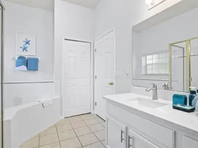 a white bathroom with a sink and a mirror at Holiday Home 3-Schlafzimmer Value Plus Haus mit privatem Pool by Interhome in Kissimmee