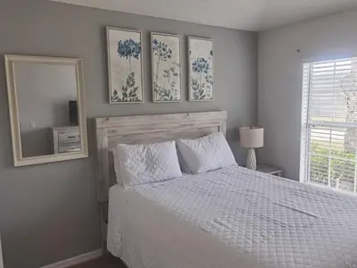 a bedroom with a white bed and a mirror at Holiday Home Seasons Retreat mit privatem Pool in der Nähe von Disney by Interhome in Kissimmee