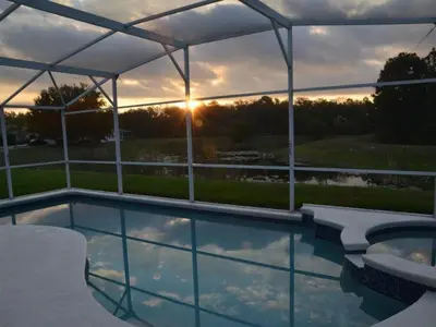 a swimming pool with a canopy and the sunset in the background at Holiday Home Familienfreundliche Villa nahe der Disney-Parks by Interhome in Orlando