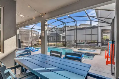 a patio with a picnic table and a swimming pool at Disney & Universal House with Pool & Arcade in Kissimmee