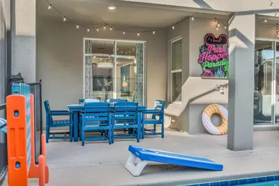 a patio with blue tables and chairs and a pool at Disney & Universal House with Pool & Arcade in Kissimmee