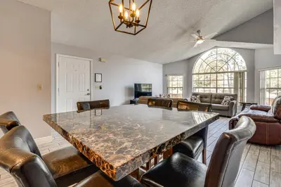 a dining room with a large marble table and leather chairs at Family Theme Park Hub with Pool in Kissimmee in Kissimmee