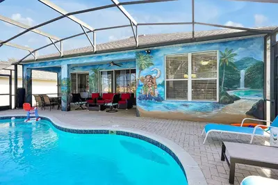a swimming pool in front of a house with a mural at 4BR Family Villa Pool Game Room Near Disney in Orlando