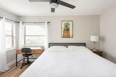 a bedroom with a bed and a desk and a fan at The Pineapple Express in Orlando