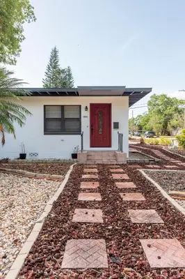 a house with a red door and a gravel driveway at The Pineapple Express in Orlando