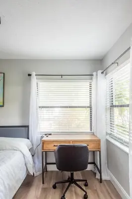 a bedroom with a desk and a bed and a window at The Pineapple Express in Orlando