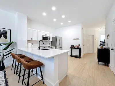 a white kitchen with a counter and stools in it at The Roundup Retreat! in Orlando