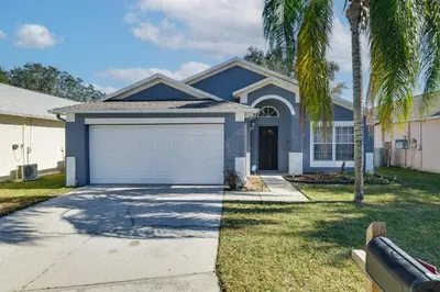 a house with a garage and a palm tree at Visit Disney and Universal Parks! Group-Friendly Gem in Orlando