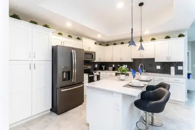 a kitchen with white cabinets and a black refrigerator at Lake view Near Disney Resort w Lazy River 108 in Kissimmee