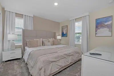 a white bedroom with a large bed and windows at 9 Bedroom With Everything For Happiness! home in Kissimmee