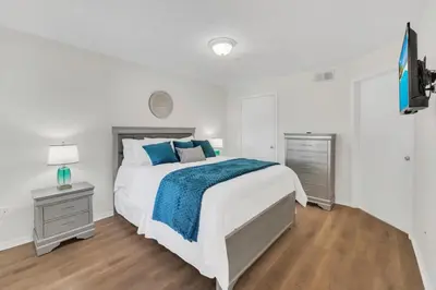 a white bedroom with a large bed and a television at Grand Luxury 2BR Penthouse near Disney Parks in Kissimmee