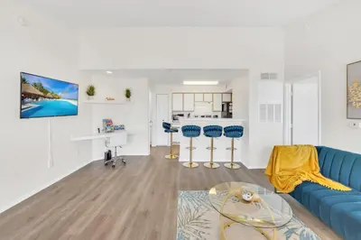 a living room with a blue couch and a kitchen at Grand Luxury 2BR Penthouse near Disney Parks in Kissimmee
