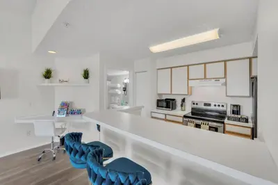 a kitchen with a white counter and blue chairs at Grand Luxury 2BR Penthouse near Disney Parks in Kissimmee