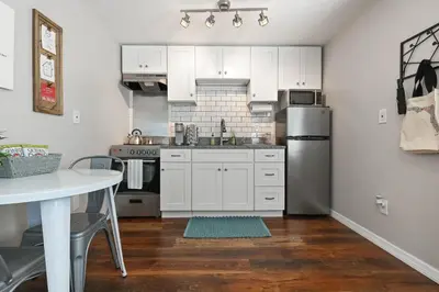 a kitchen with white cabinets and a stainless steel refrigerator at Bungalow near Universal, Disney, and Downtown Orlando in Orlando
