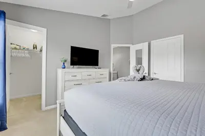 a white bedroom with a bed and a flat screen tv at Disney Min Away - Pool Patio & BBQ in Orlando