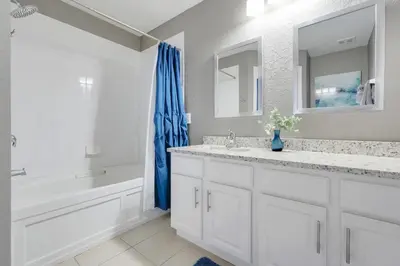 a bathroom with white cabinets and a blue shower curtain at Disney Min Away - Pool Patio & BBQ in Orlando