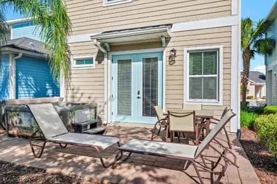 a patio with chairs and a table in front of a house at Tropical Cottage With Hot Tub Near Disney With Margaritaville Resort And Island H20 Waterpark Access - 8040Dr in Orlando