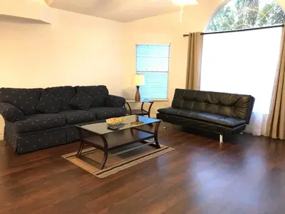 a living room with a black couch and a table at 10 minutes to all Disney parks with pool and wifi in Kissimmee