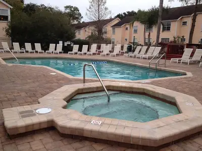 a swimming pool with chairs and a hot tub at 10 minutes to all Disney parks with pool and wifi in Kissimmee