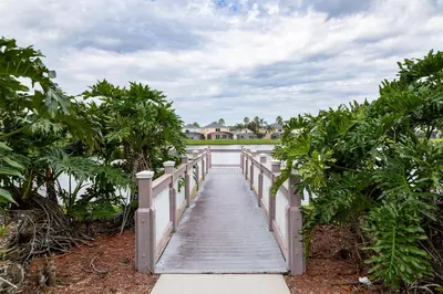 a wooden bridge over a body of water with trees at Peaceful Palms Stay for 6 in Kissimmee
