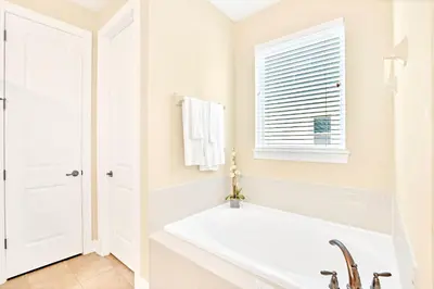 a white bathroom with a tub and a window at 7668 Wilmington Loop in Orlando