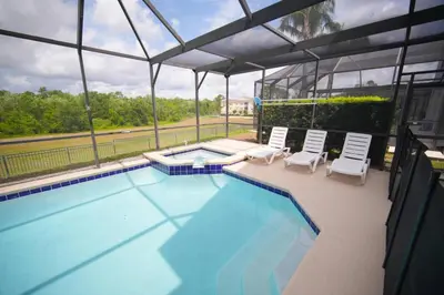 a swimming pool with two white chairs and a swimming poolvisor at 6BR Family Vacation Home near Disney in Kissimmee