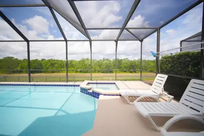 a swimming pool with two lawn chairs and a swimming pool at 6BR Family Vacation Home near Disney in Kissimmee