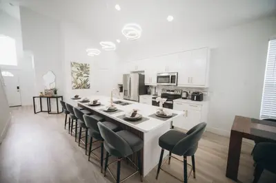 a kitchen with a large white island with chairs at 6BR Family Vacation Home near Disney in Kissimmee