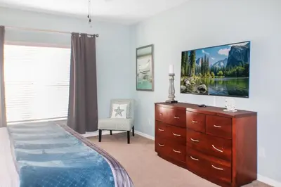a bedroom with a dresser and a tv on the wall at Family Private Home W Heated Pool 12Min To Walt Disney in Kissimmee