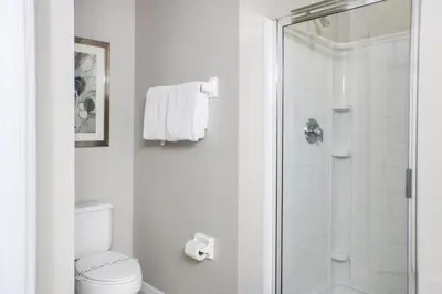 a white bathroom with a shower and a toilet at Family Private Home W Heated Pool 12Min To Walt Disney in Kissimmee