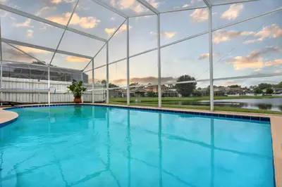 a large swimming pool in a building with glass walls at Lakefront Home Game Room & Views in Kissimmee