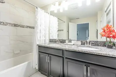 a bathroom with two sinks and a shower and a tub at 4BR Townhome w Pool in Storey Lake - Near Disney in Kissimmee