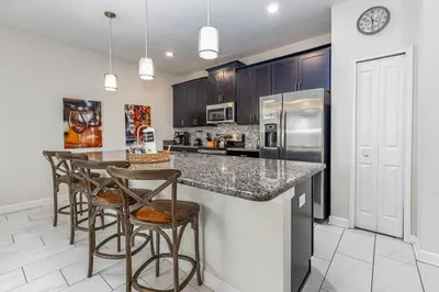 a kitchen with a counter with chairs and a refrigerator at 4BR Townhome w Pool in Storey Lake - Near Disney in Kissimmee