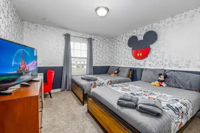 a bedroom with two beds and a flat screen tv at 4BR Townhome w Pool in Storey Lake - Near Disney in Kissimmee
