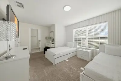 a white bedroom with a bed and a desk at Cozy 5 Bedrooms and 4 Bathrooms At Storey Lake in Kissimmee