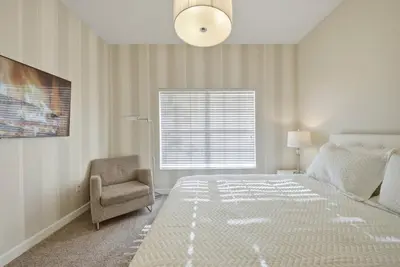 a bedroom with a bed and a chair and a window at Cozy 5 Bedrooms and 4 Bathrooms At Storey Lake in Kissimmee