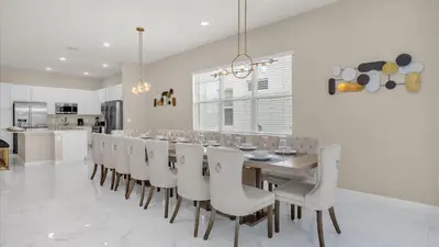 a dining room with a long table and white chairs at Upstay Spacious Villa w Pool, Hot Tub & Game Room in Kissimmee
