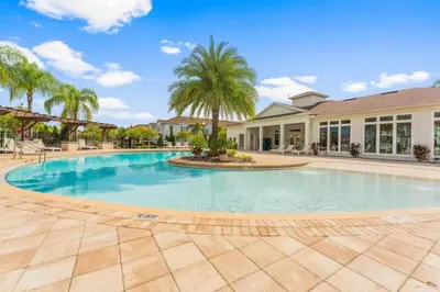 a large swimming pool with palm trees and a building at Townhome 4Q Temático — 15min da Disney in Kissimmee