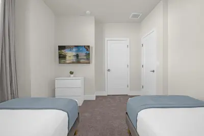 two beds in a room with white walls at Luxury 4 Bedroom Family Getaway w Private Pool in Orlando