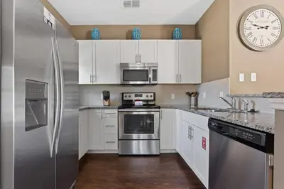 a kitchen with stainless steel appliances and a clock on the wall at Townhome 4Q no West Lucaya — 15min Disney in Kissimmee