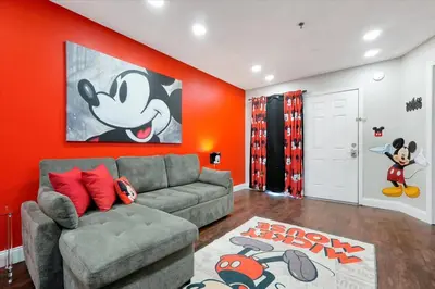 a living room with a gray couch and an orange wall at Mickey Family Condo - 4 Miles to Disney in Orlando