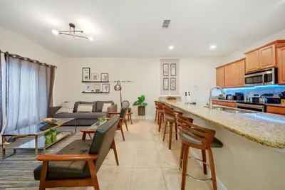 a kitchen and living room with a counter and chairs at Cozy Home Luxury 04 Bedrooms At Storey Lake in Kissimmee