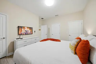 a white bedroom with a bed and a flat screen tv at Cozy Home Luxury 04 Bedrooms At Storey Lake in Kissimmee