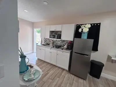 a kitchen with white cabinets and a refrigerator with flowers at Private Guesthouse in Orlando