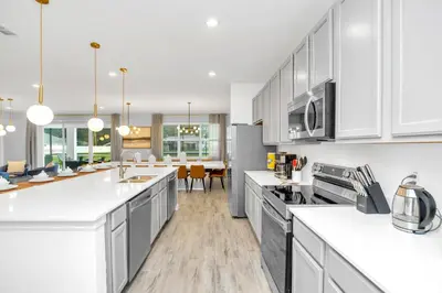 a kitchen with white cabinets and a dining room at Luxurious 15-Bedroom Villa With Pool & Games Room in Kissimmee