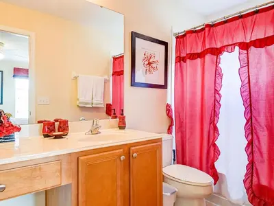 a bathroom with a sink and a toilet and red curtains at Ev2753 - Golden Horizon Villa in Kissimmee