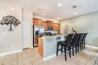 an open kitchen with a bar with black chairs at Ev8944 - Paradise Palms Escape in Kissimmee